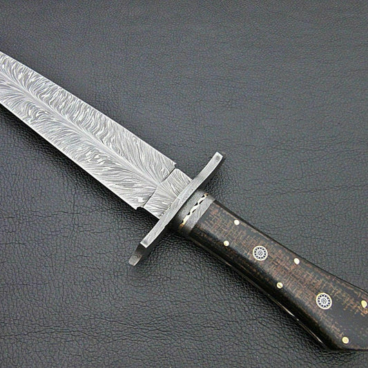 Close up of handmade Damascus steel Bowie knife blade showing distinctive black feather pattern