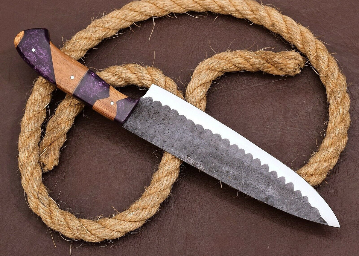 Close-up of a Damascus steel kitchen knife showing a hammered, acid etched blade finish and a striking purple and wood handle with pin detail.